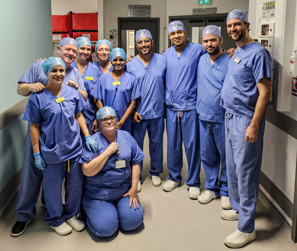 Members of NHSGGC staff in blue surgical scrubs, pose for a picture in the Institute of Neurological Sciences.