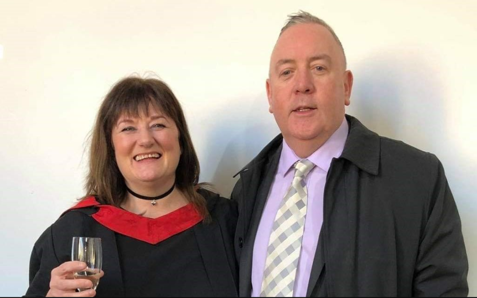 Smiling woman holding glass of champagne on her graduation day alongside her husband