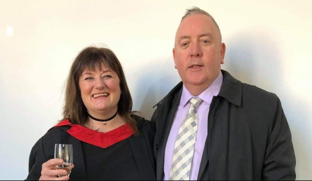 Smiling woman holding glass of champagne on her graduation day alongside her husband