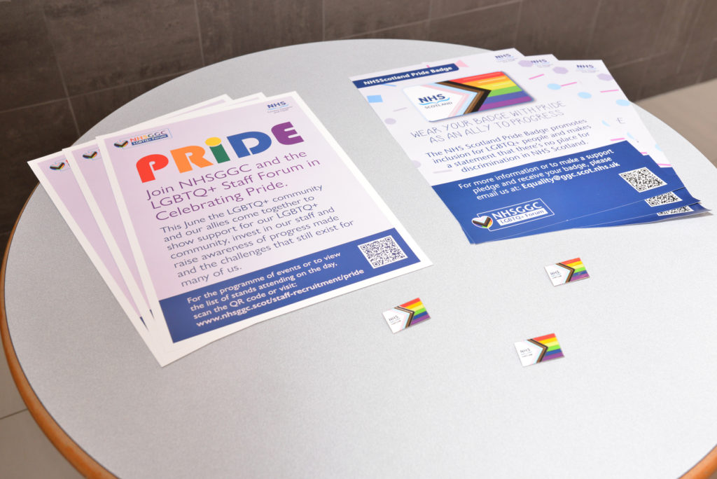 Posters, and NHS Scotland Pride Pledge, on a table.