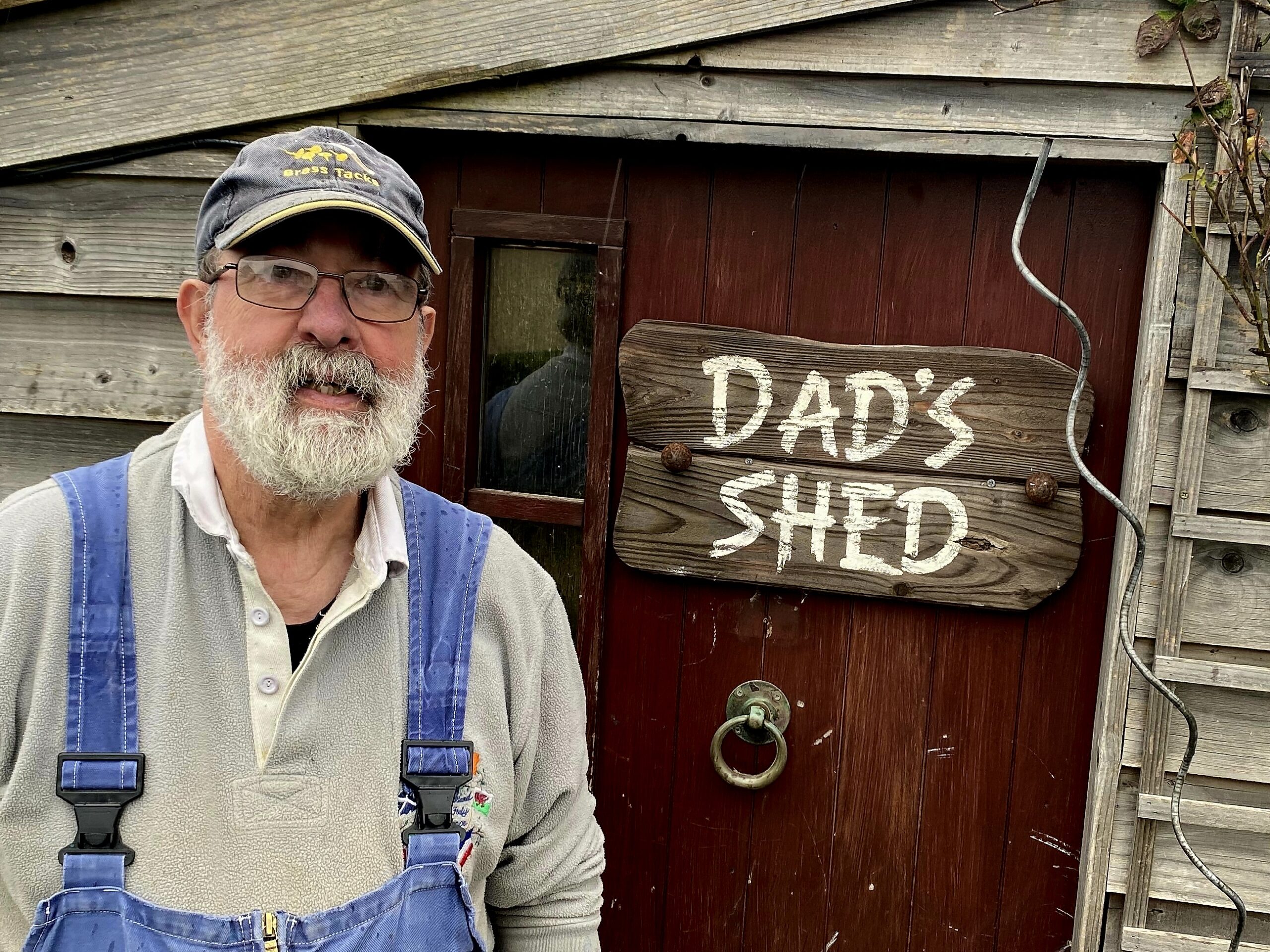 Campbell McDonald beside door to his workshop, with sign saying 'Dad's Shed' on the door.