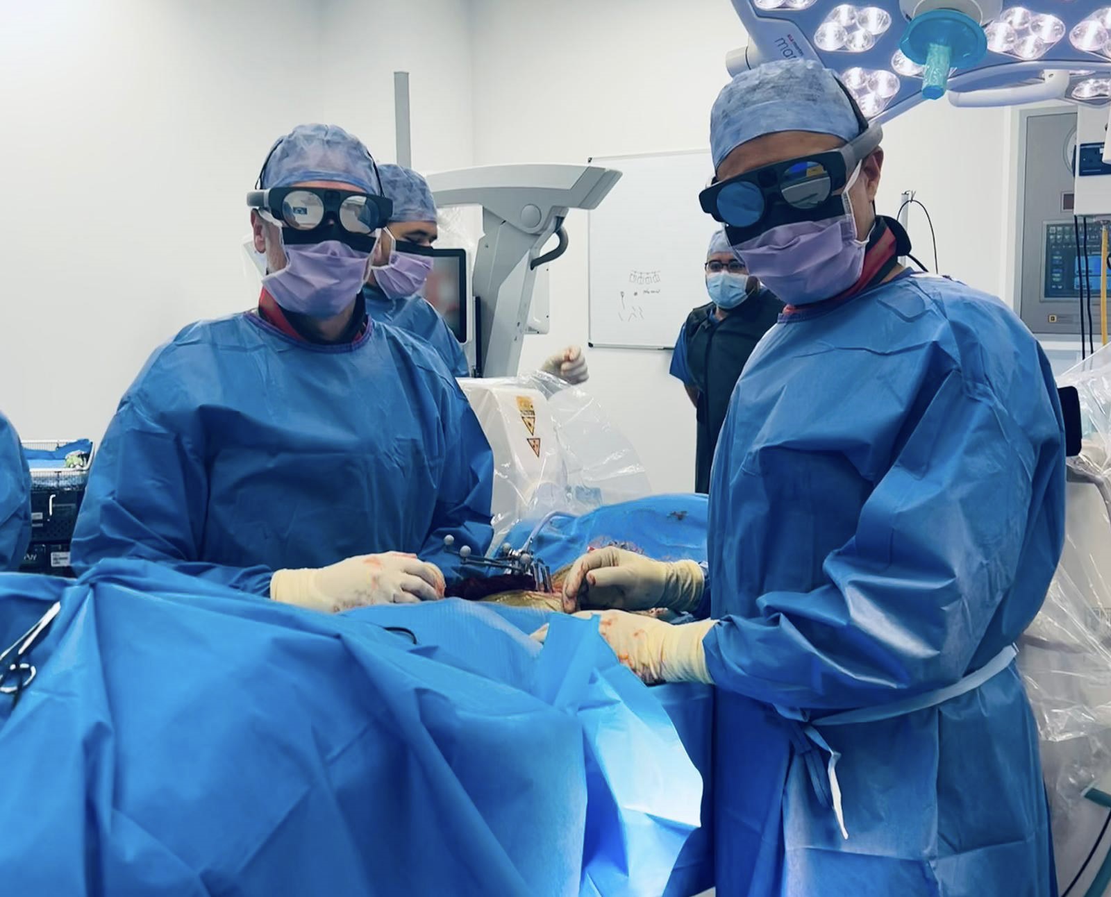 Two surgeons in an operating theatre, wearing the new Mixed Reality goggles.