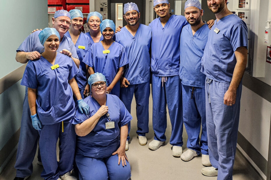 Members of NHSGGC staff in blue surgical scrubs, pose for a picture in the Institute of Neurological Sciences.